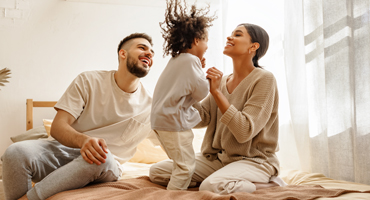 image of a family playing with their daughter on the bed