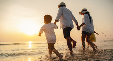 family holding hands walking into the beach water