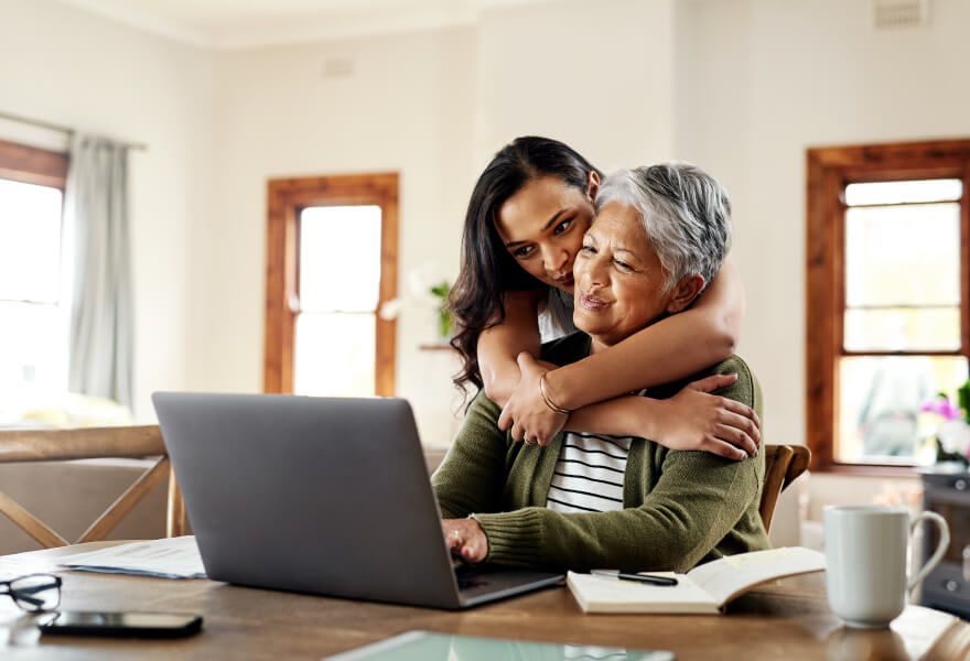 Woman hugging Grandmother looking over laptop